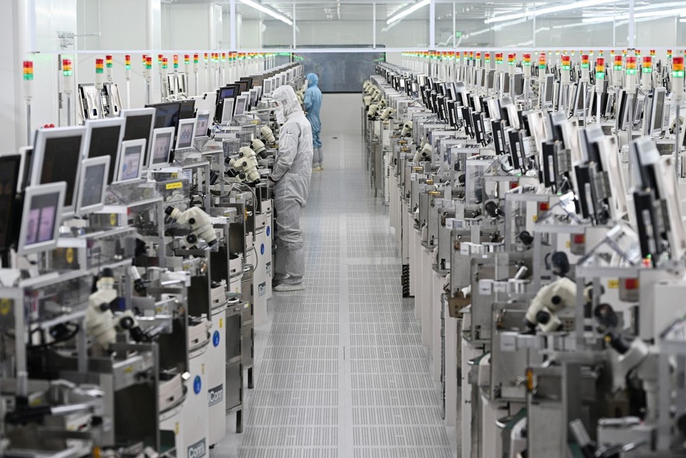 Funcionários trabalham em equipamentos de processamento de chips em uma fábrica de semicondutores em Suqian, na província de Jiangsu, no leste da China — Foto: Foto por STR / AFP