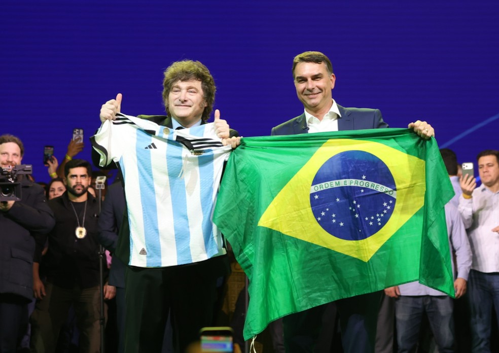 O presidente da Argentina, Javier Milei, e o senador Flávio Bolsonaro durante convenção do PL — Foto: Leco Viana/Thenews2/Agência O Globo