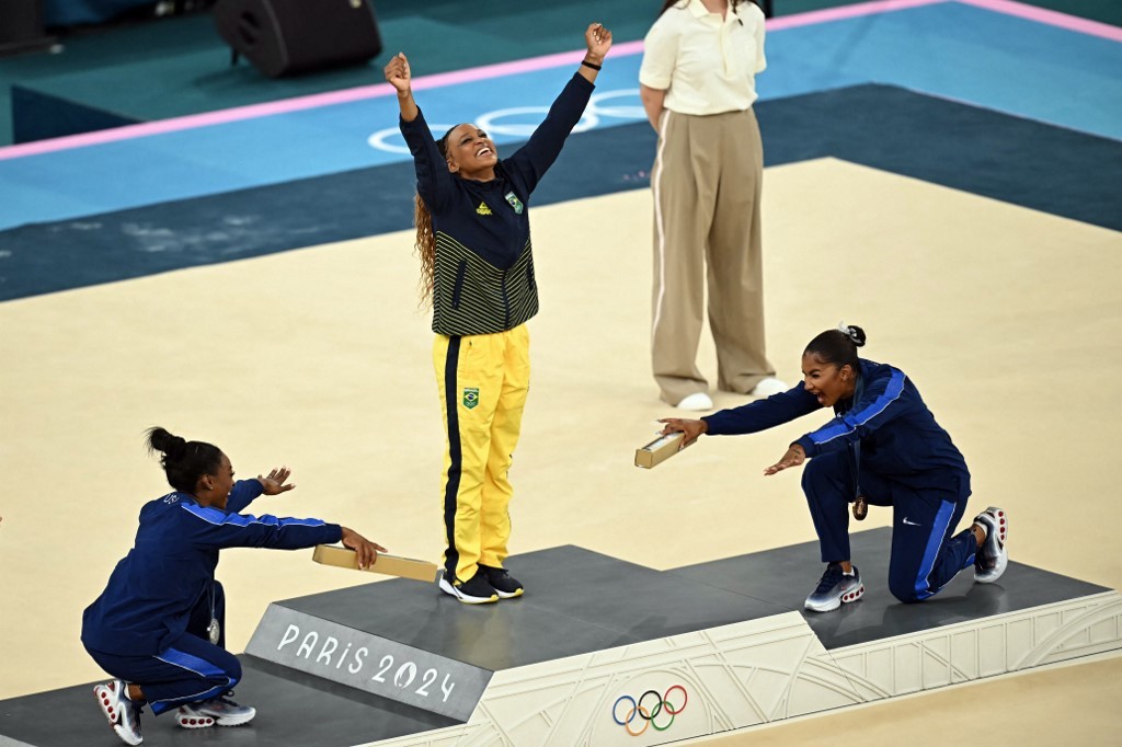 Rebeca Andrade é homenageada por Simone Biles e Jordan Chiles no pódio em Paris 2024. — Foto: Paul ELLIS / AFP