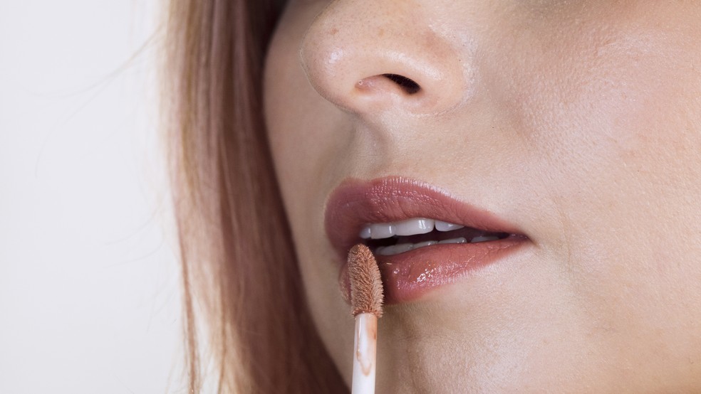 Mulher passa gloss nos lábios — Foto: Freepik